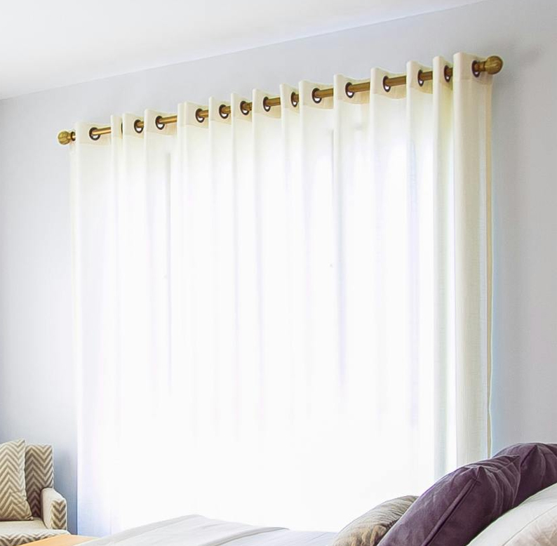 White soundproof curtains hanging in front of a window.